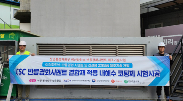 롯데건설 직원들이 부산 롯데타워 현장에서 ‘이산화탄소 반응경화 시멘트’를 활용한 코팅제를 시공하고 기념촬영을 했다. 사진=롯데건설